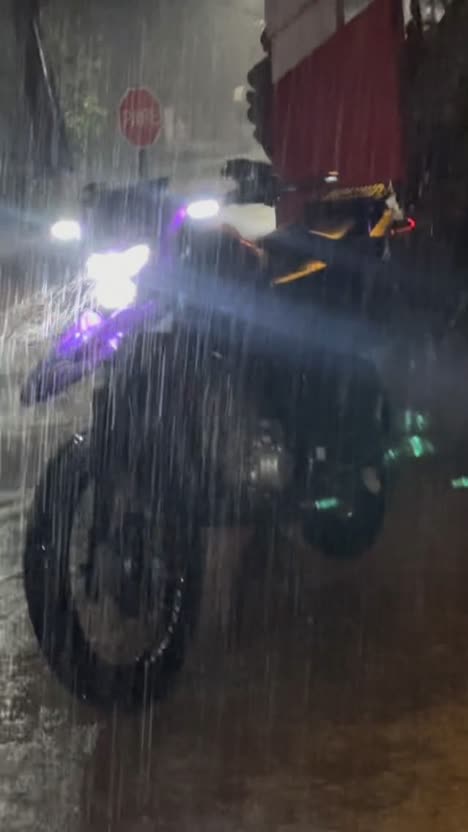 First frame of the analysed post: a motorcycle at night in heavy rain, headlight glowing.