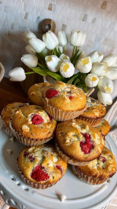 First frame of the analysed post: raspberry muffins piled on a cake stand in front of white tulips.