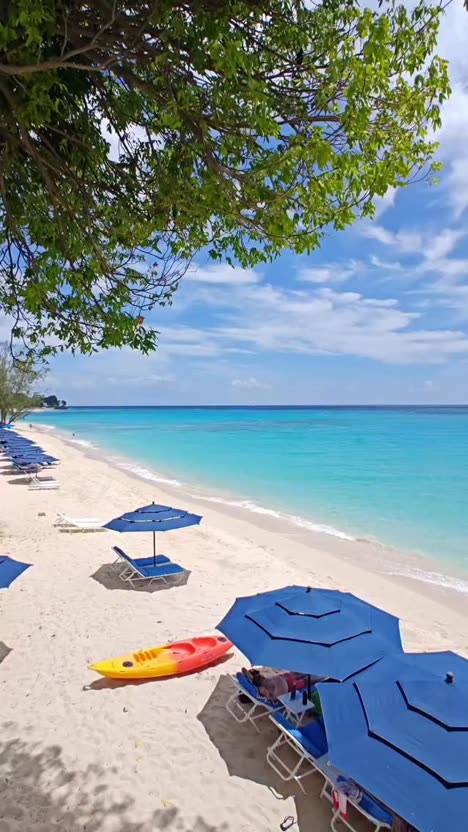 First frame of the analysed post: a vivid tropical beach with turquoise water, white sand and blue umbrellas.